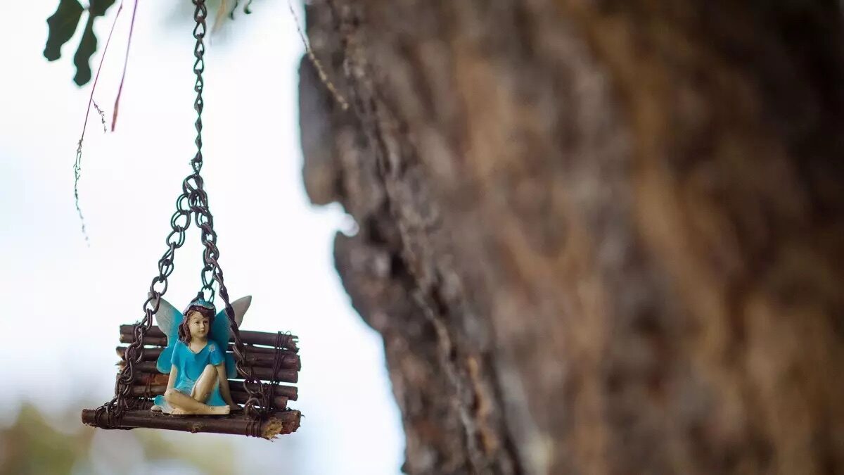 A fairy on a handmade swing hanging from a branch